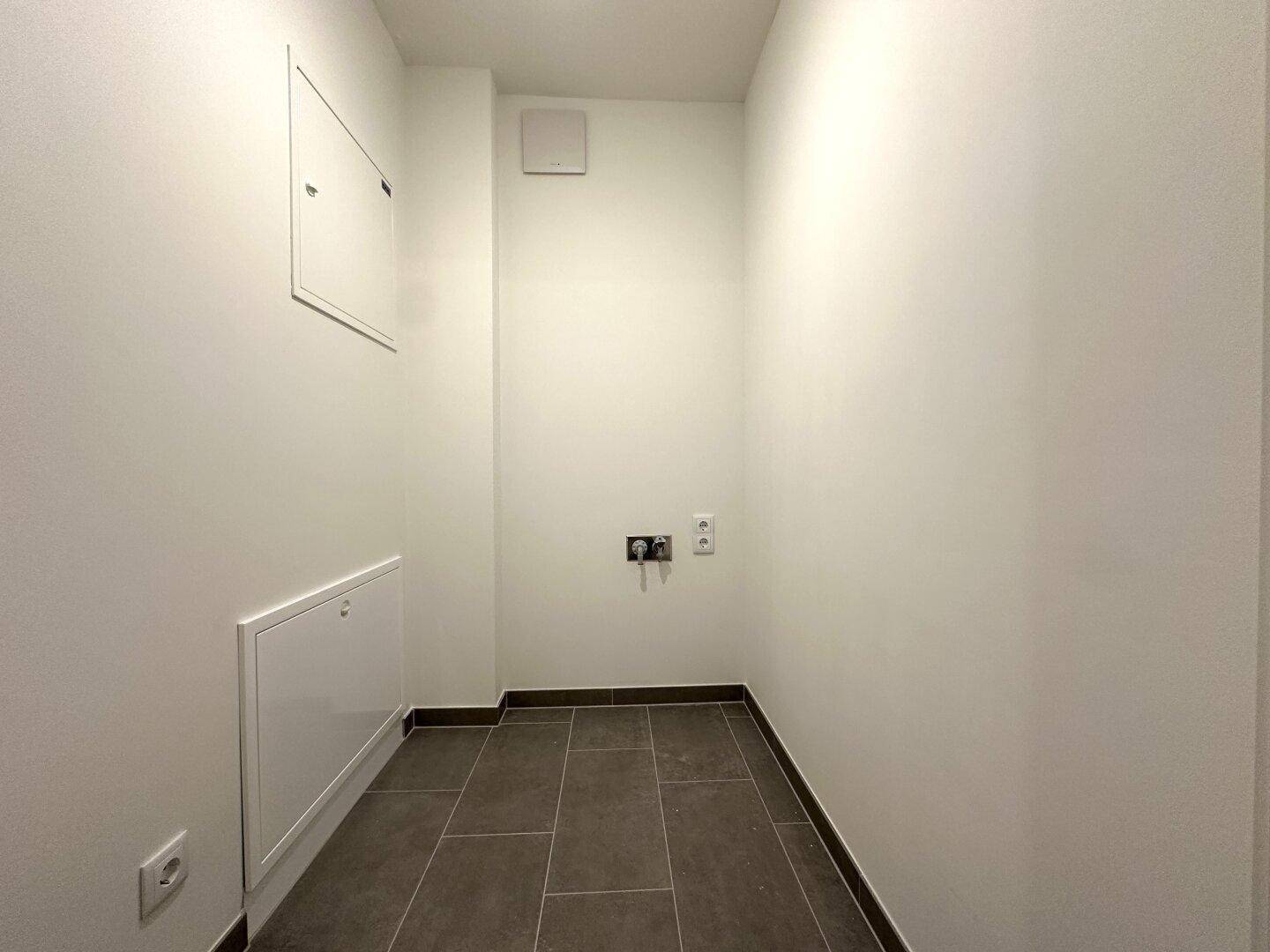 Praktischer Hauswirtschaftsraum mit Fliesenboden und Anschlüssen für Waschmaschine.