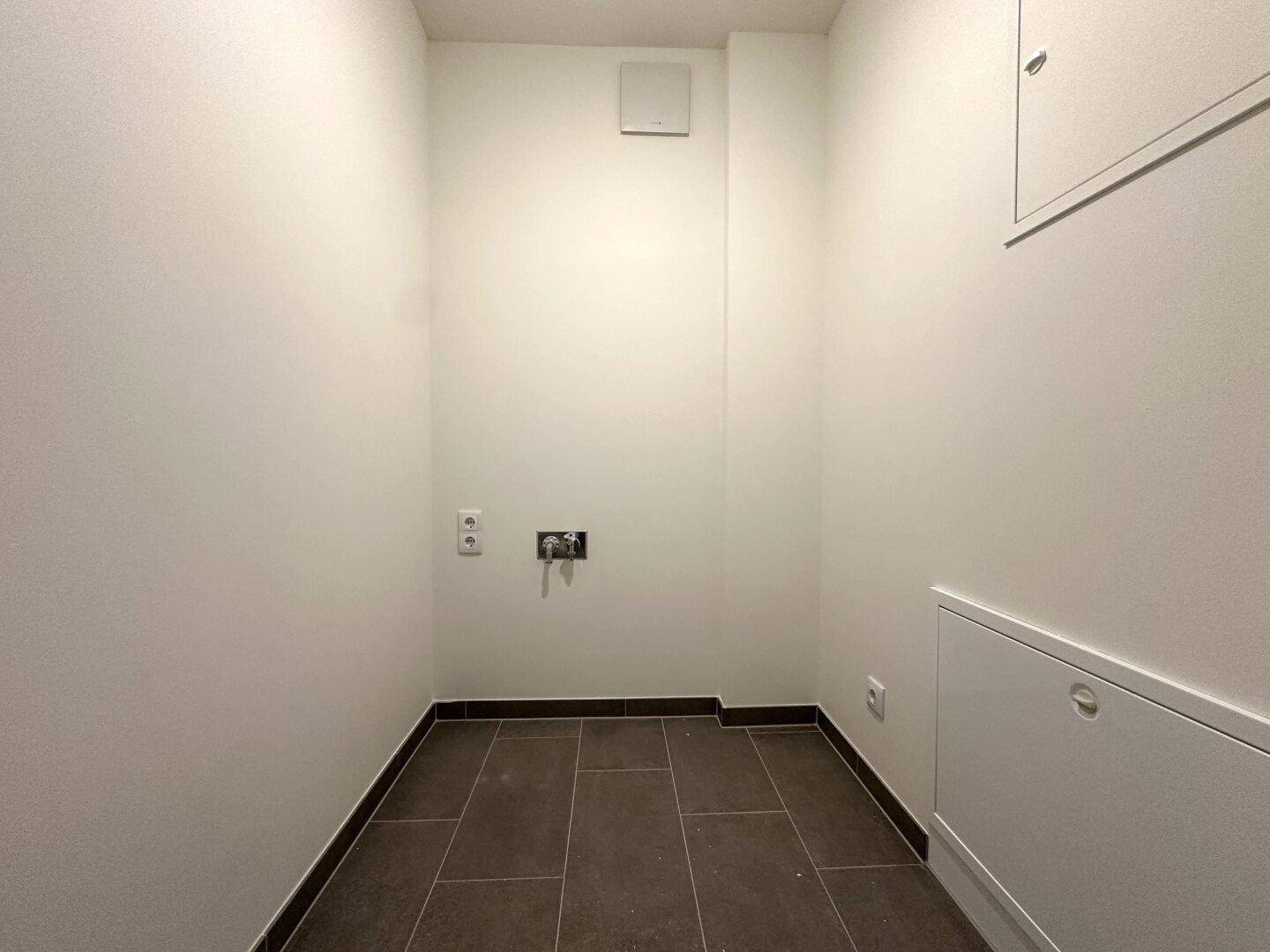 Praktischer Hauswirtschaftsraum mit Fliesenboden und Anschlüssen für Waschmaschine.