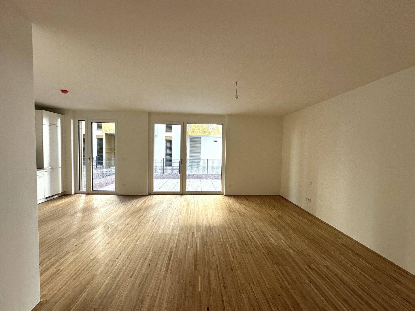 Geräumiger, lichtdurchfluteter Wohnbereich mit Holzboden und großen Terrassentüren.