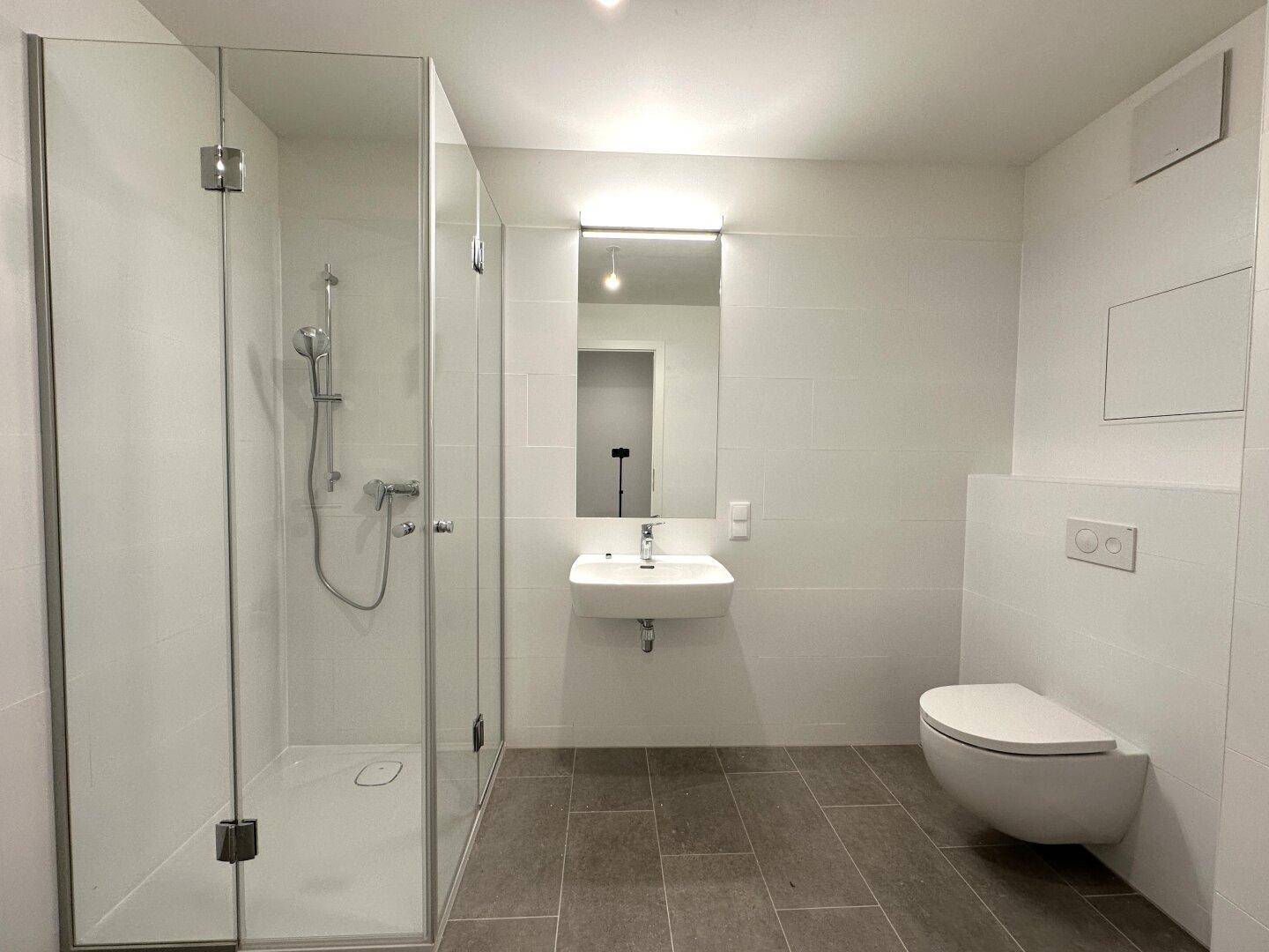 Modernes Badezimmer mit ebenerdiger Dusche, Wand-WC und großformatigen Fliesen.