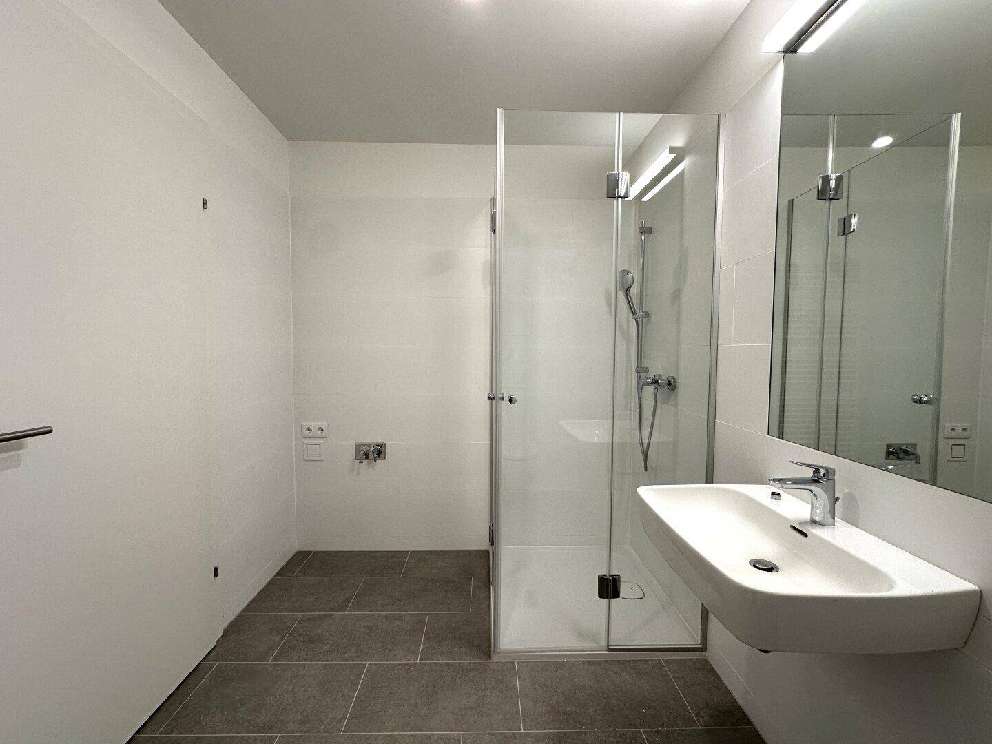 Helles Badezimmer mit moderner Duschkabine und Waschbecken.