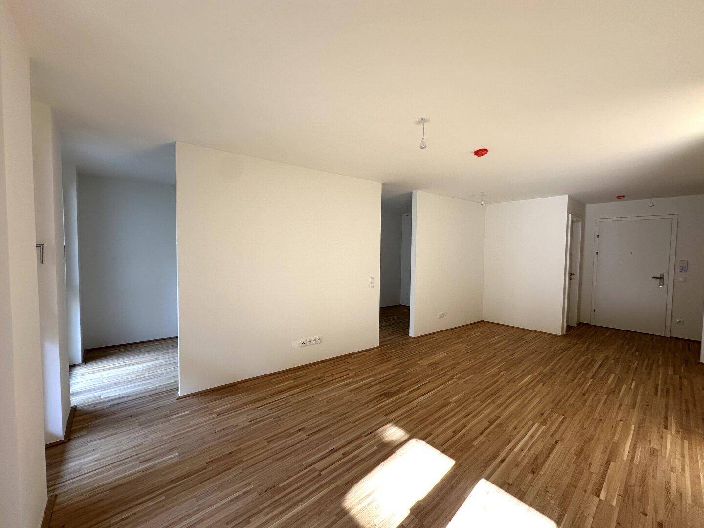 Geräumiger Wohnbereich mit Parkettboden und weiß gestrichenen Wänden, ideal für individuelle Gestaltung.