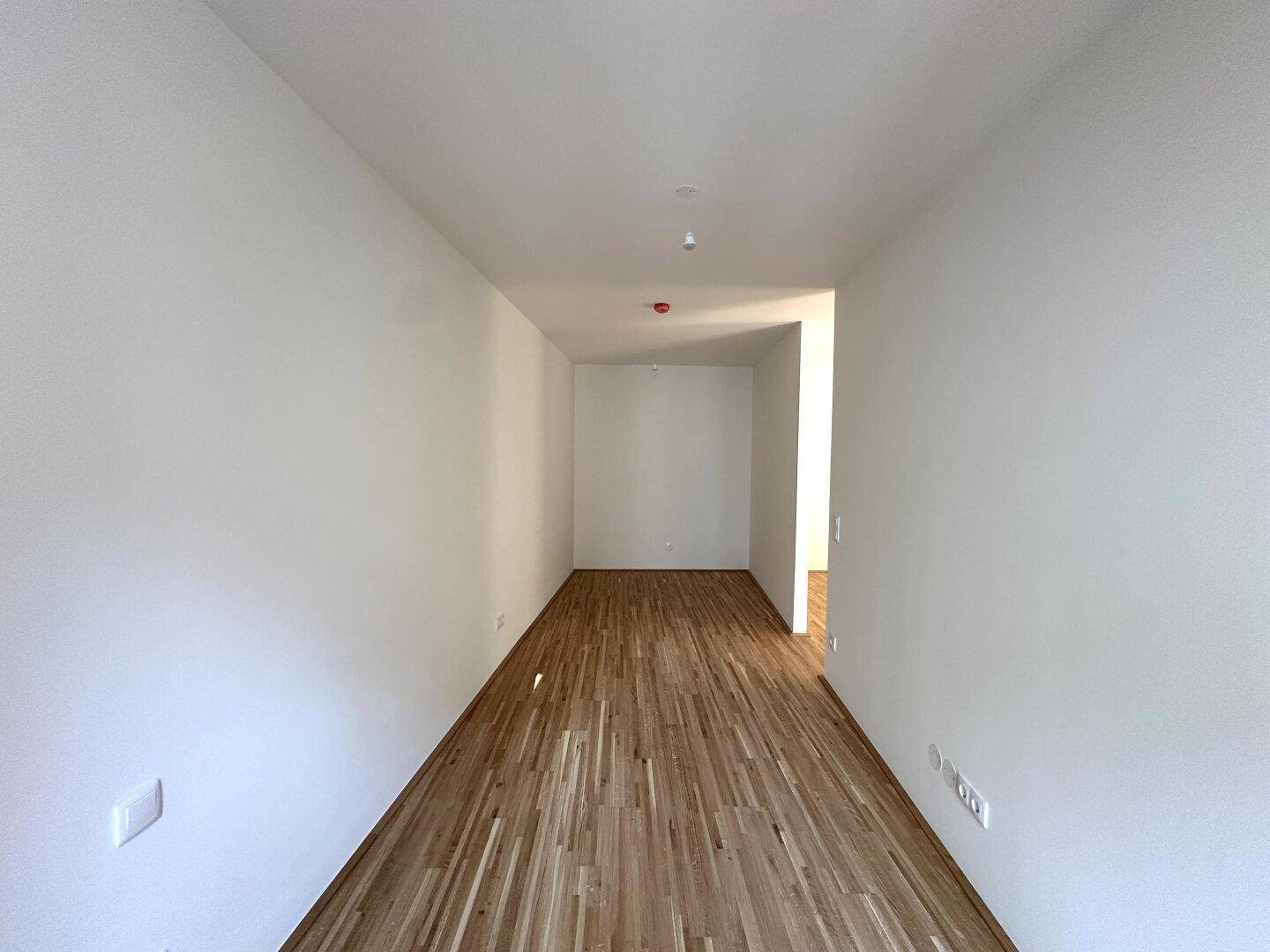 Langer, heller Flur mit Parkettboden, der zu den verschiedenen Räumen der Wohnung führt.