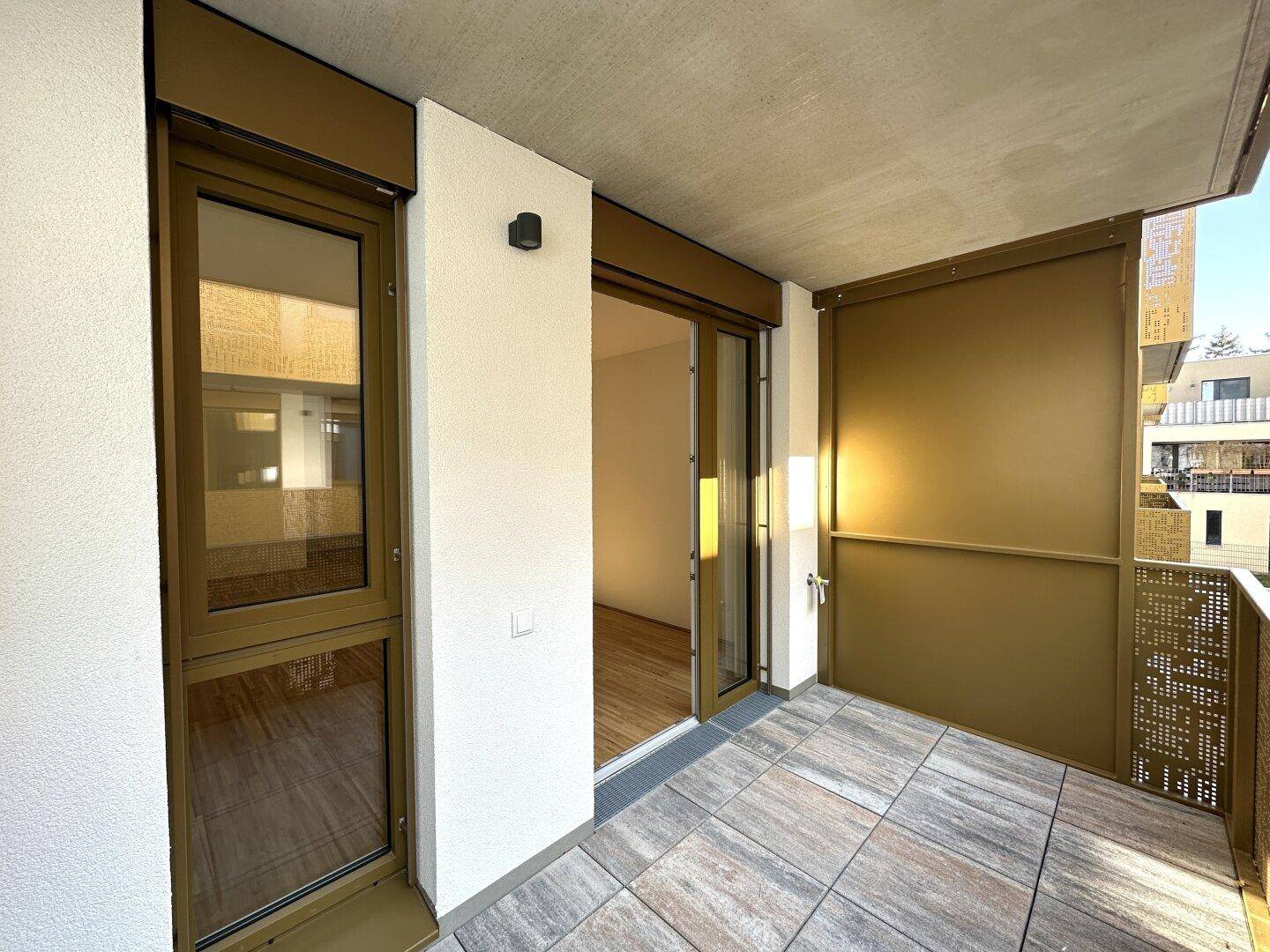 Heller Balkon mit Fliesenboden und Zugang von der Wohnung, bietet Platz für Outdoor-Möbel.