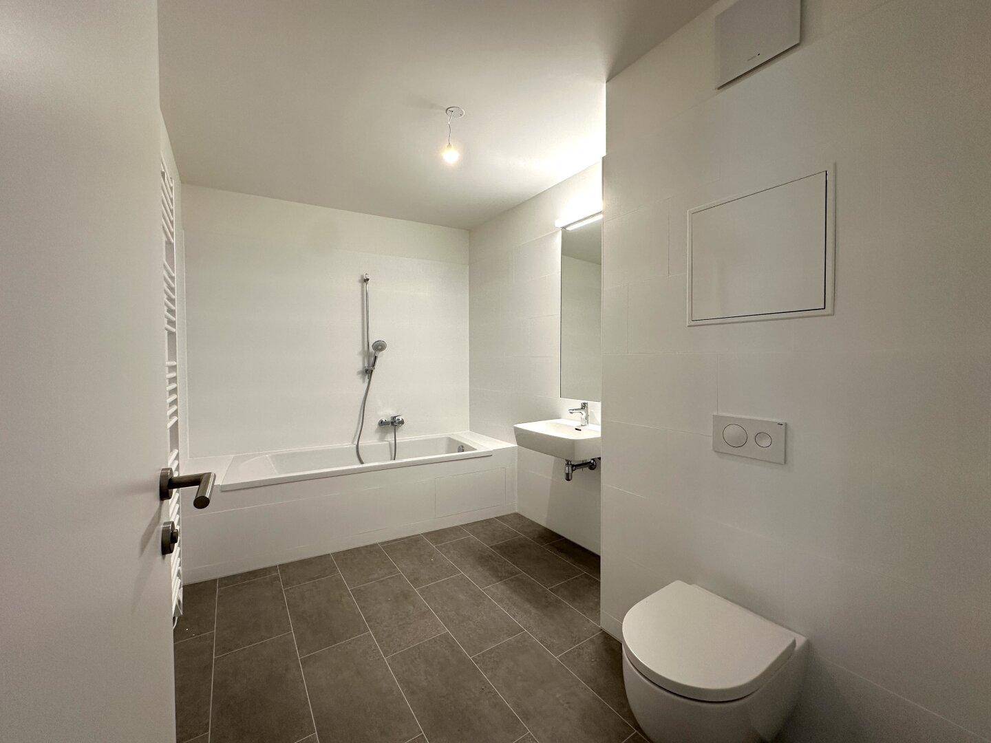 Helles Badezimmer mit Badewanne, Waschbecken und wandhängendem WC, alles in modernem Design.
