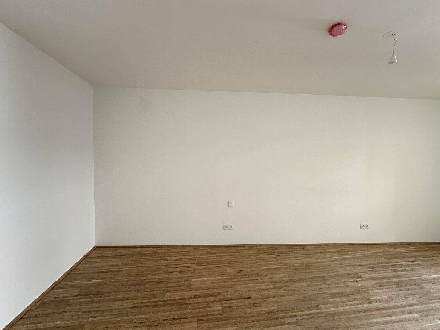 Leerer Raum mit hellen Wänden und Holzboden, bereit für die individuelle Gestaltung.