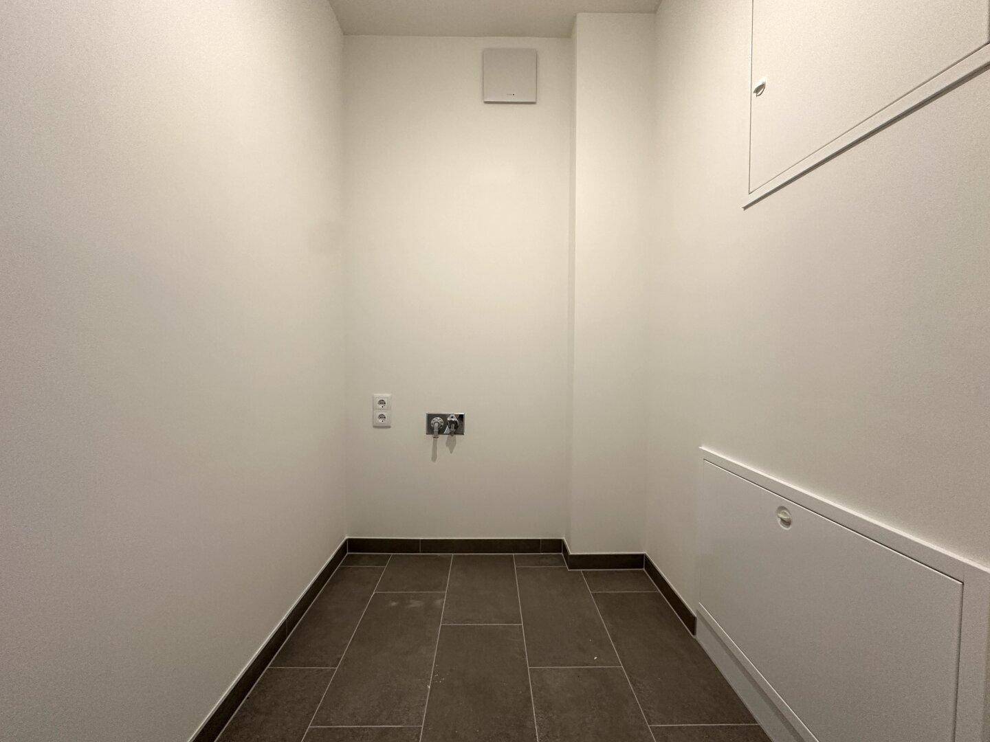 Kleiner Hauswirtschaftsraum mit Fliesenboden und Anschlüssen für Waschmaschine.