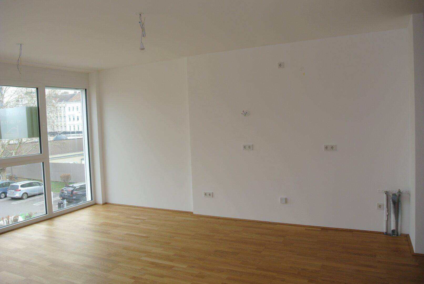 Geräumiger, heller Wohnbereich mit Parkettboden und großen Fenstern, die einen Stadtblick bieten.