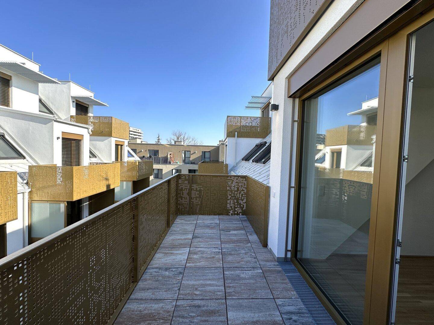 Geräumiger Balkon mit Fliesenboden und moderner Metallbrüstung, bietet Blick auf die Umgebung.
