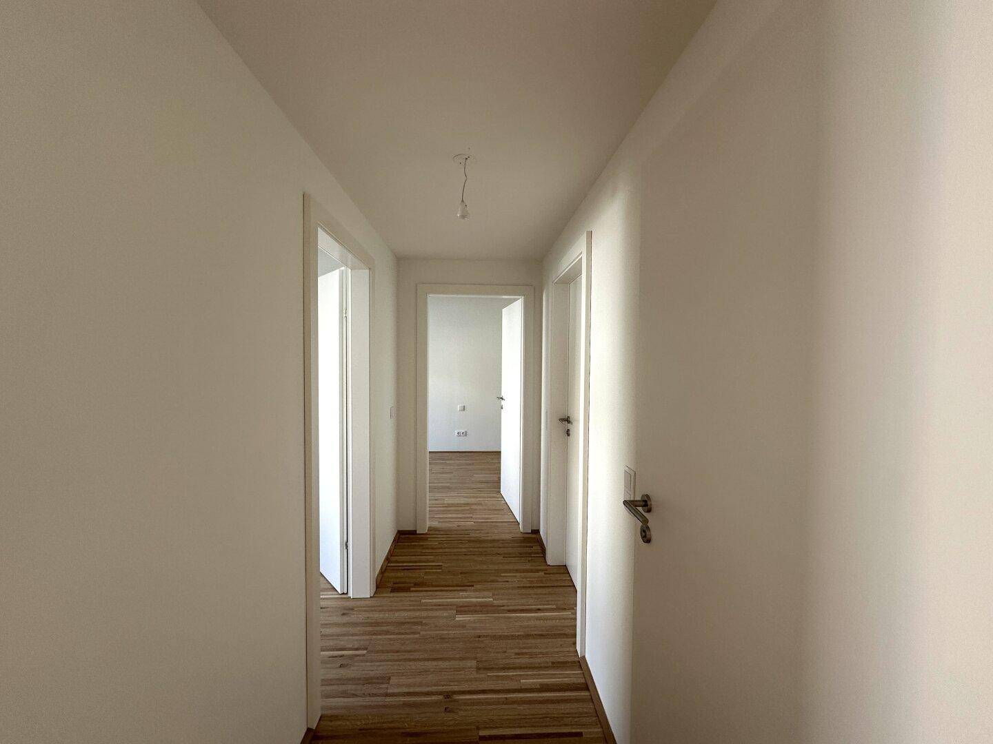 Heller Flur mit Holzboden und mehreren Türen, die zu den angrenzenden Räumen führen.