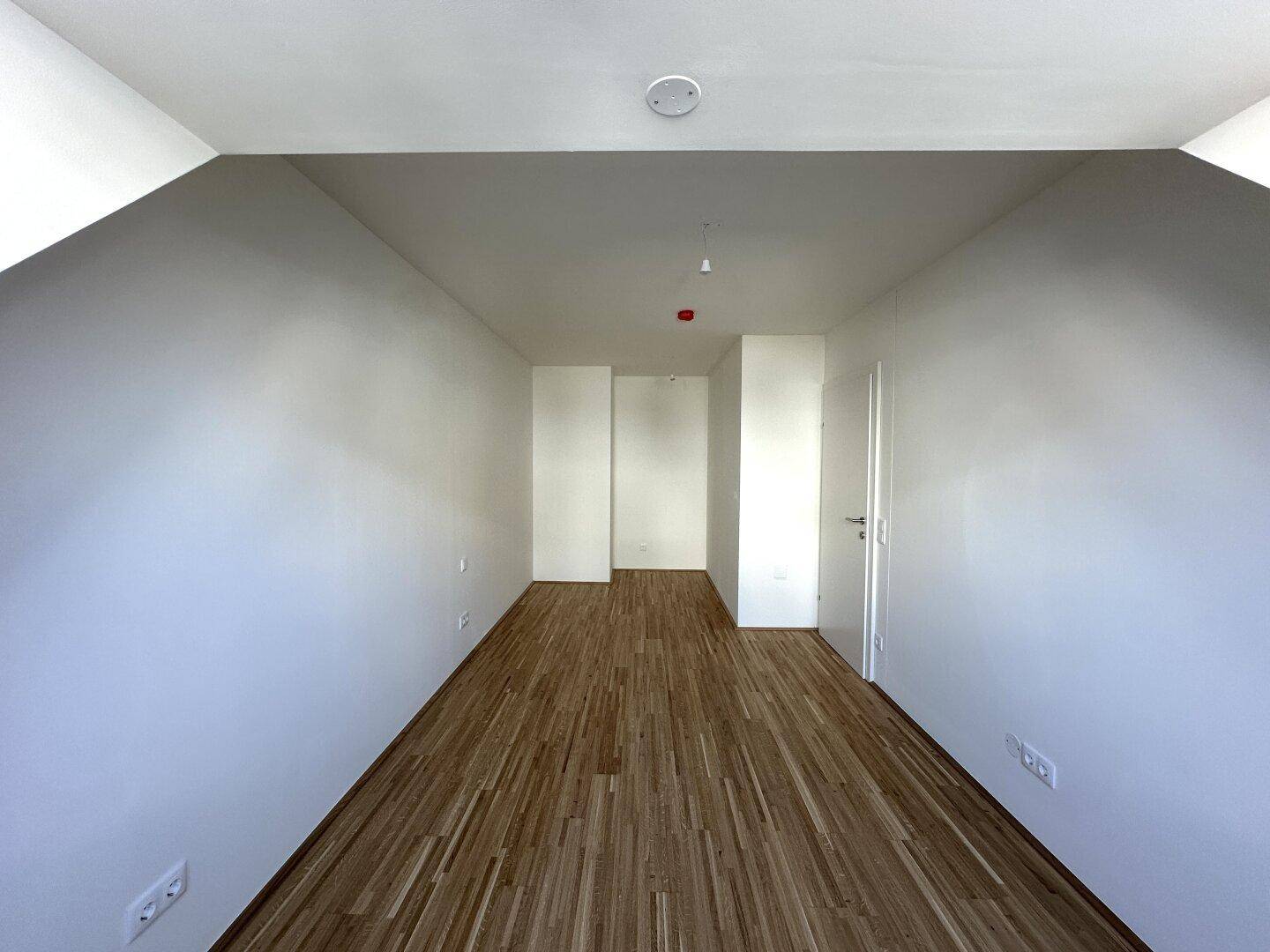 Geräumiges Zimmer mit Holzboden und weißen Wänden, bietet flexible Gestaltungsmöglichkeiten.