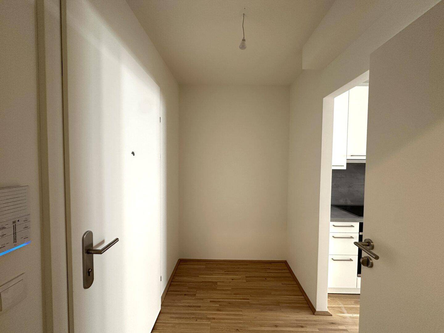 Heller Flur mit Parkettboden und Blick in die angrenzende Küche.