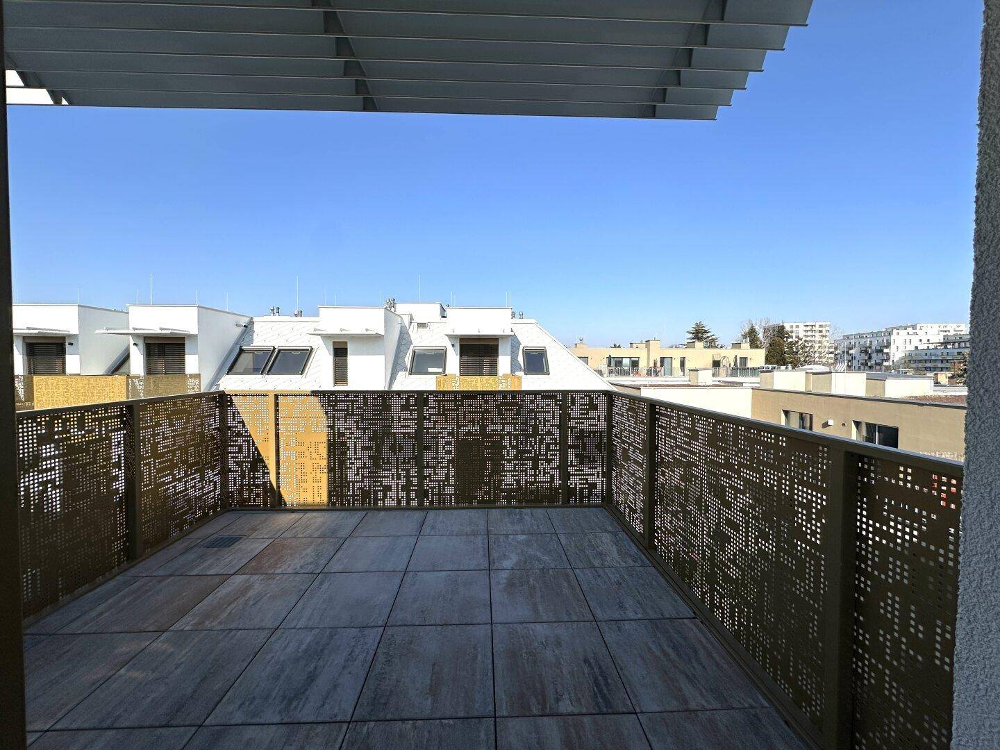 Große Dachterrasse mit modernen perforierten Geländern und einem weiten Blick über die Umgebung.