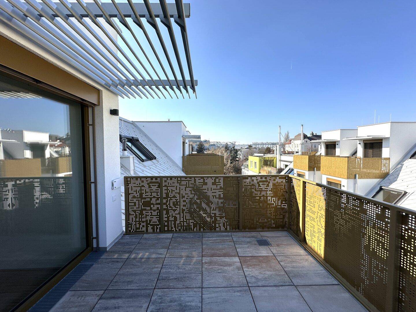 Sonnige Dachterrasse mit perforiertem Geländer und Blick auf die Stadt, ideal zum Entspannen.