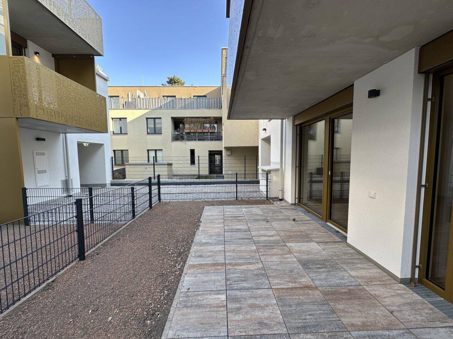Private Terrasse mit Steinplatten und Blick auf den Innenhof des modernen Wohnkomplexes.