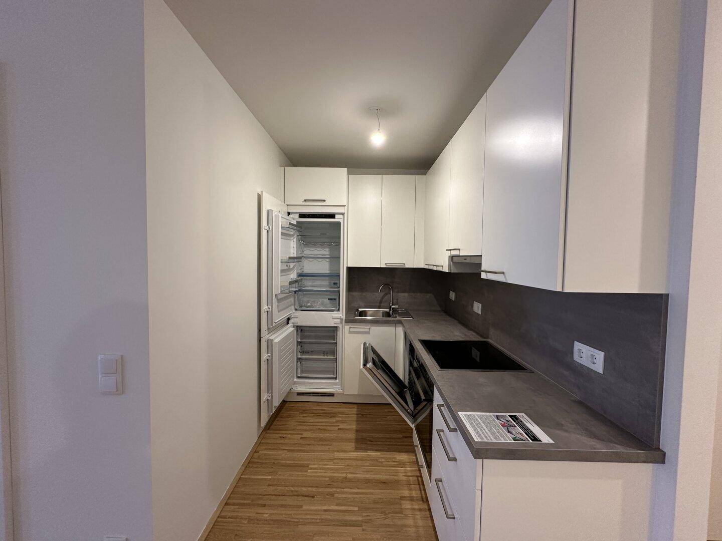Moderne Einbauküche mit geöffnetem Kühlschrank und Geschirrspüler, bereit zur Nutzung.