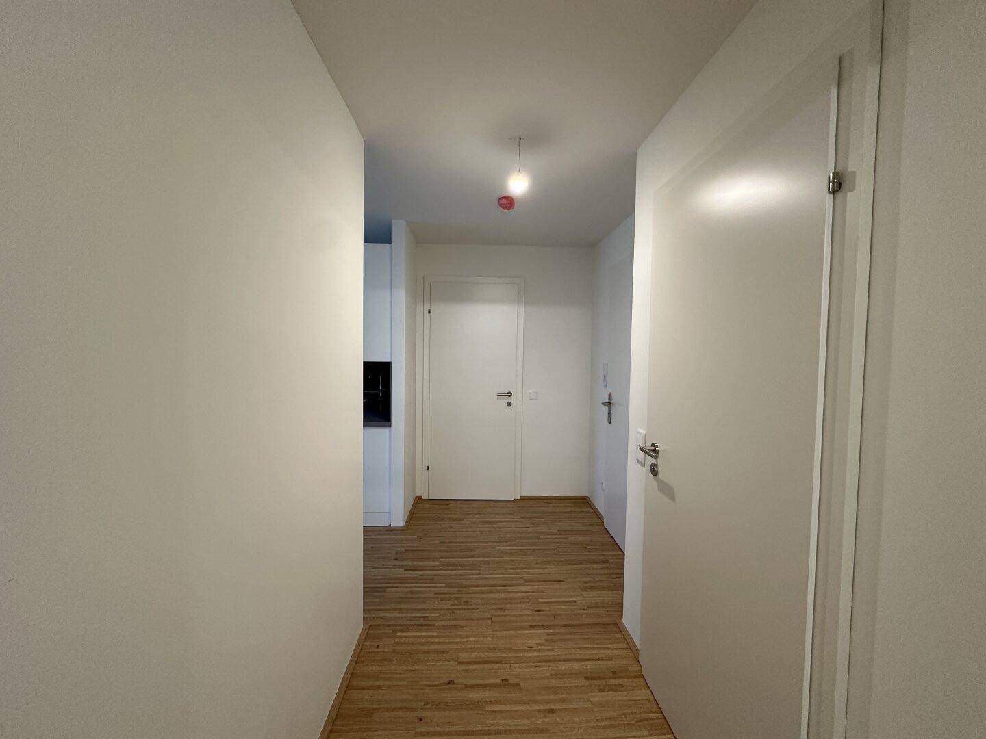 Heller Flur mit Parkettboden und weißen Türen, führt zu den verschiedenen Räumen.