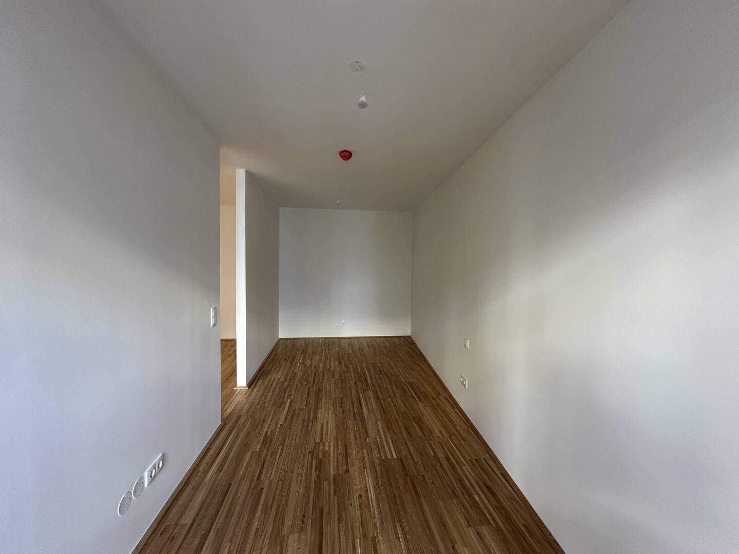 Leerer Raum mit Parkettboden und weißen Wänden, bereit zur individuellen Gestaltung.