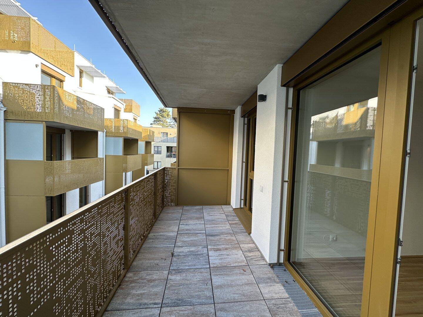 Geräumiger Balkon mit modernen perforierten Geländern und Fliesenboden, sonnig gelegen.
