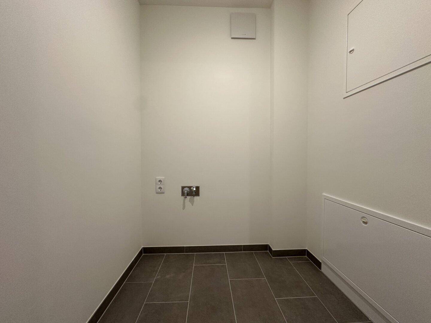 Praktischer Hauswirtschaftsraum mit Fliesenboden und Anschlüssen für Waschmaschine und Trockner.