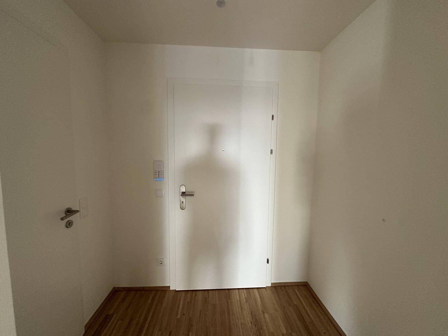 Heller Eingangsbereich mit Holzboden und weißer Tür, bietet einen freundlichen Empfang.