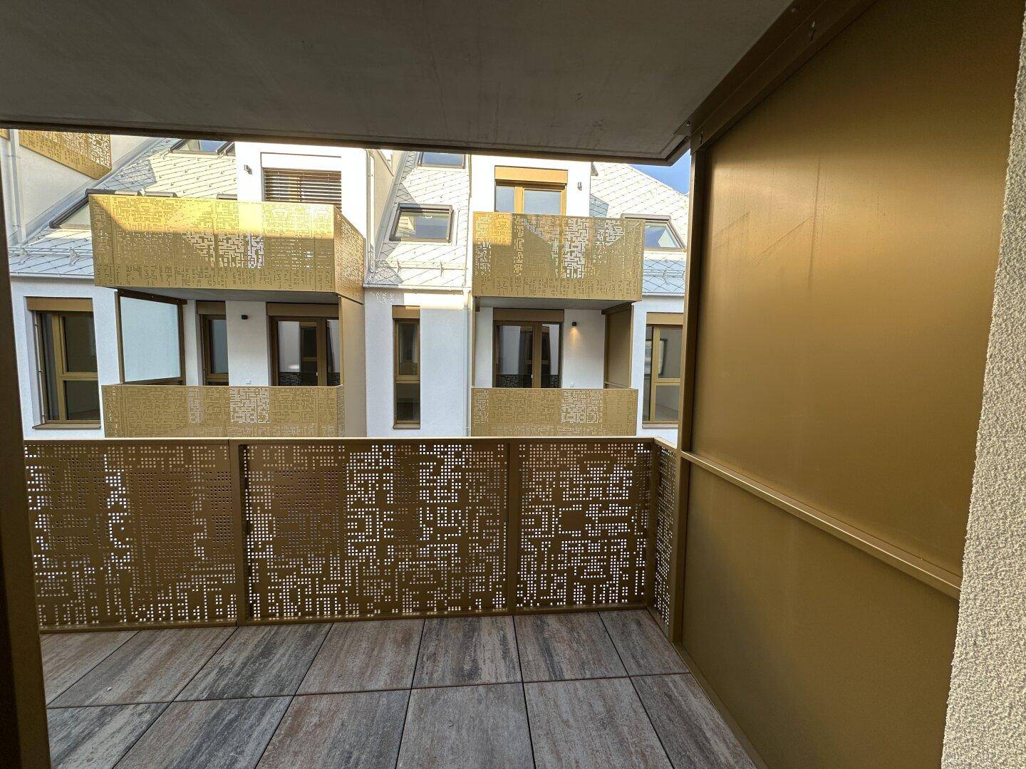 Balkon mit modernem perforiertem Geländer und Blick auf die gegenüberliegenden Gebäudebalkone.