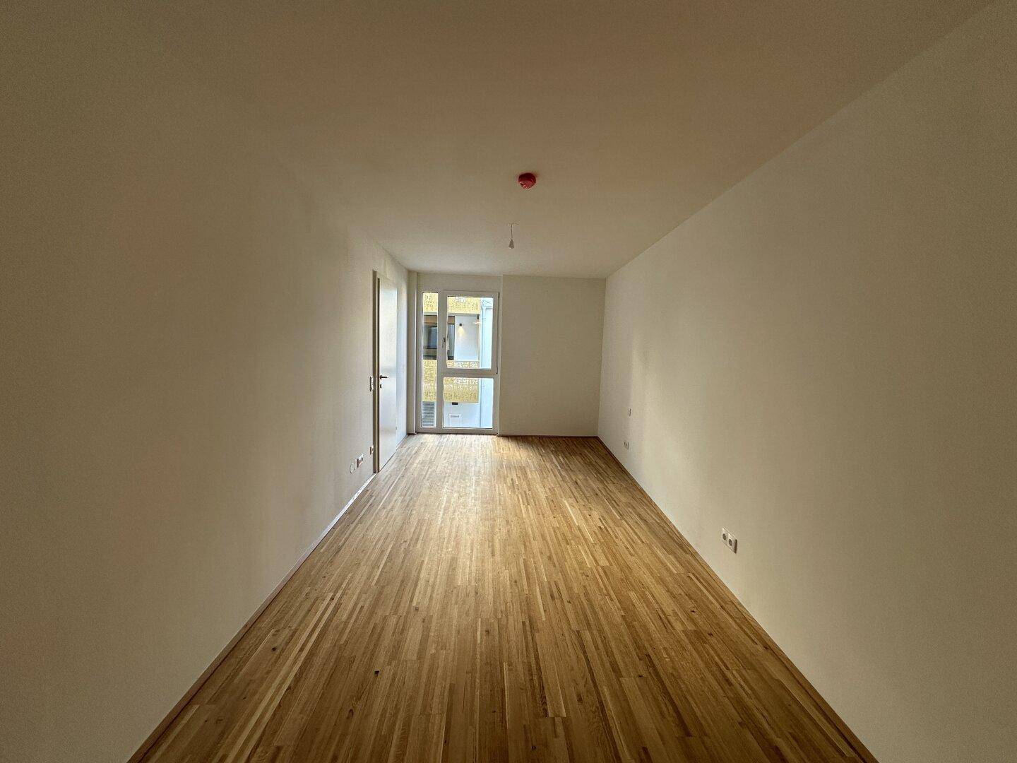 Helles Schlafzimmer mit Parkettboden und Zugang zu einem Fenster, bereit zur individuellen Gestaltung.