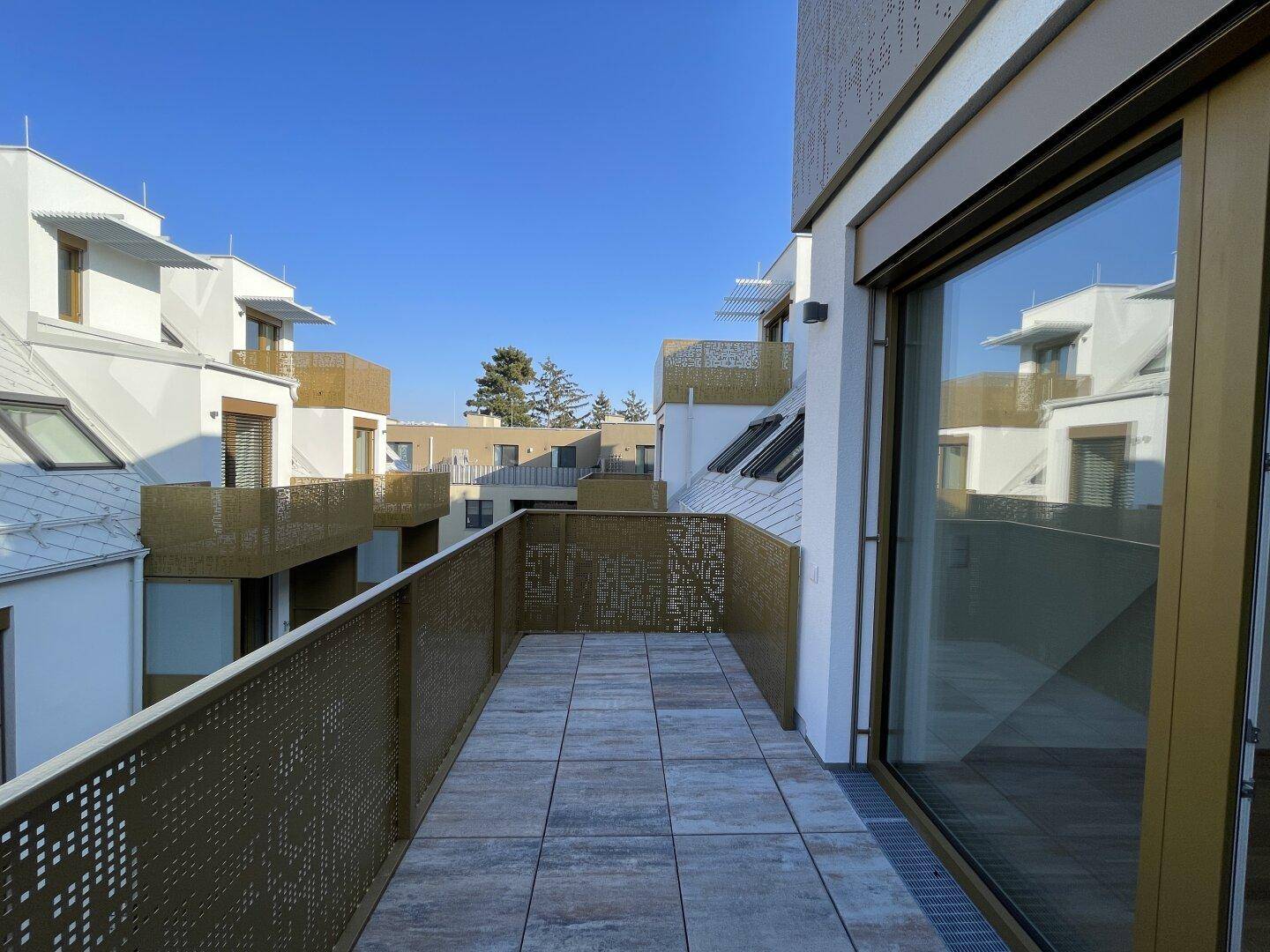 Geräumiger Balkon mit modernen Fliesen und Blick auf die umliegenden Gebäude.