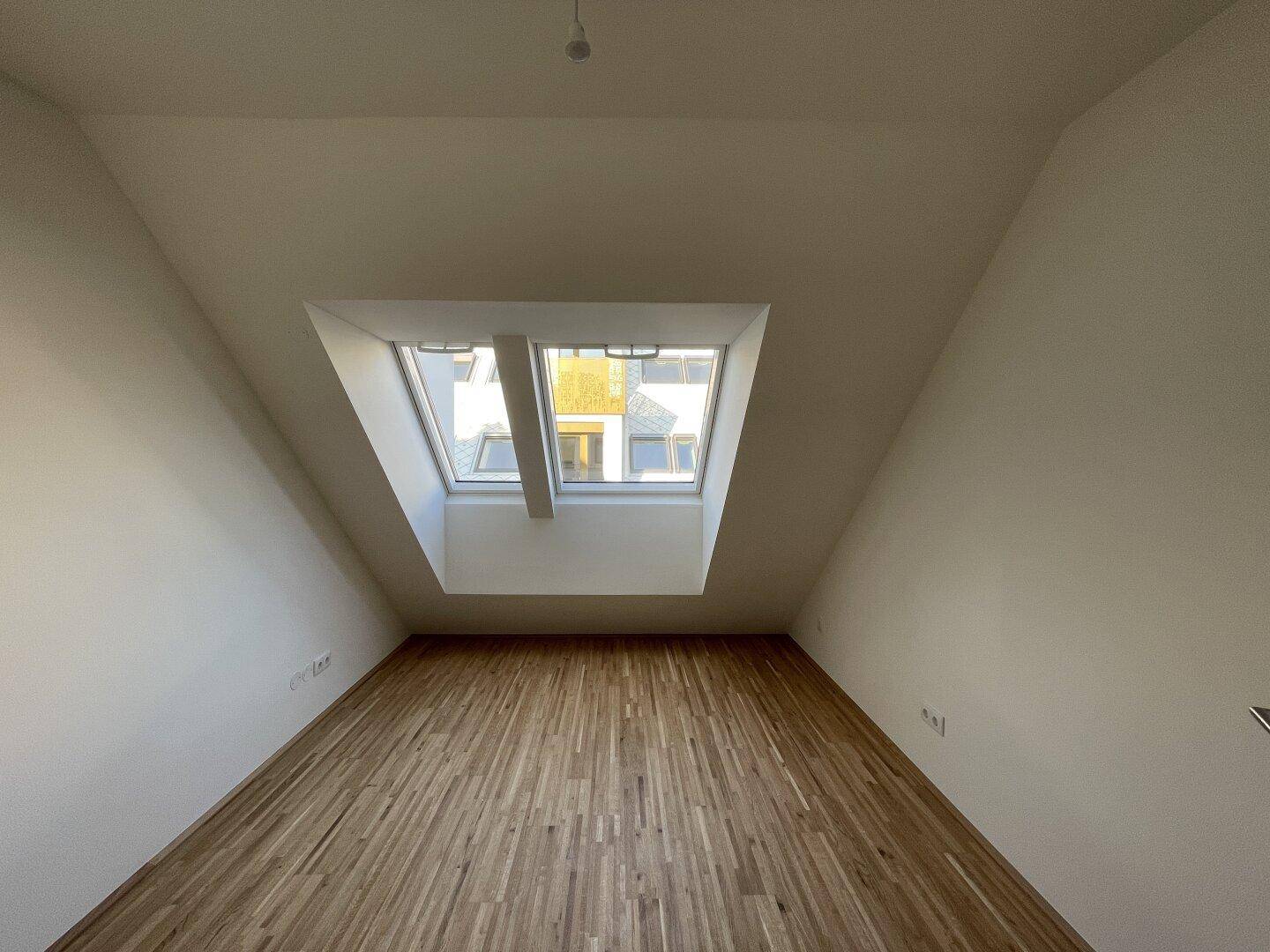 Schlafzimmer mit Dachschrägen und großen Dachfenstern für viel Tageslicht.