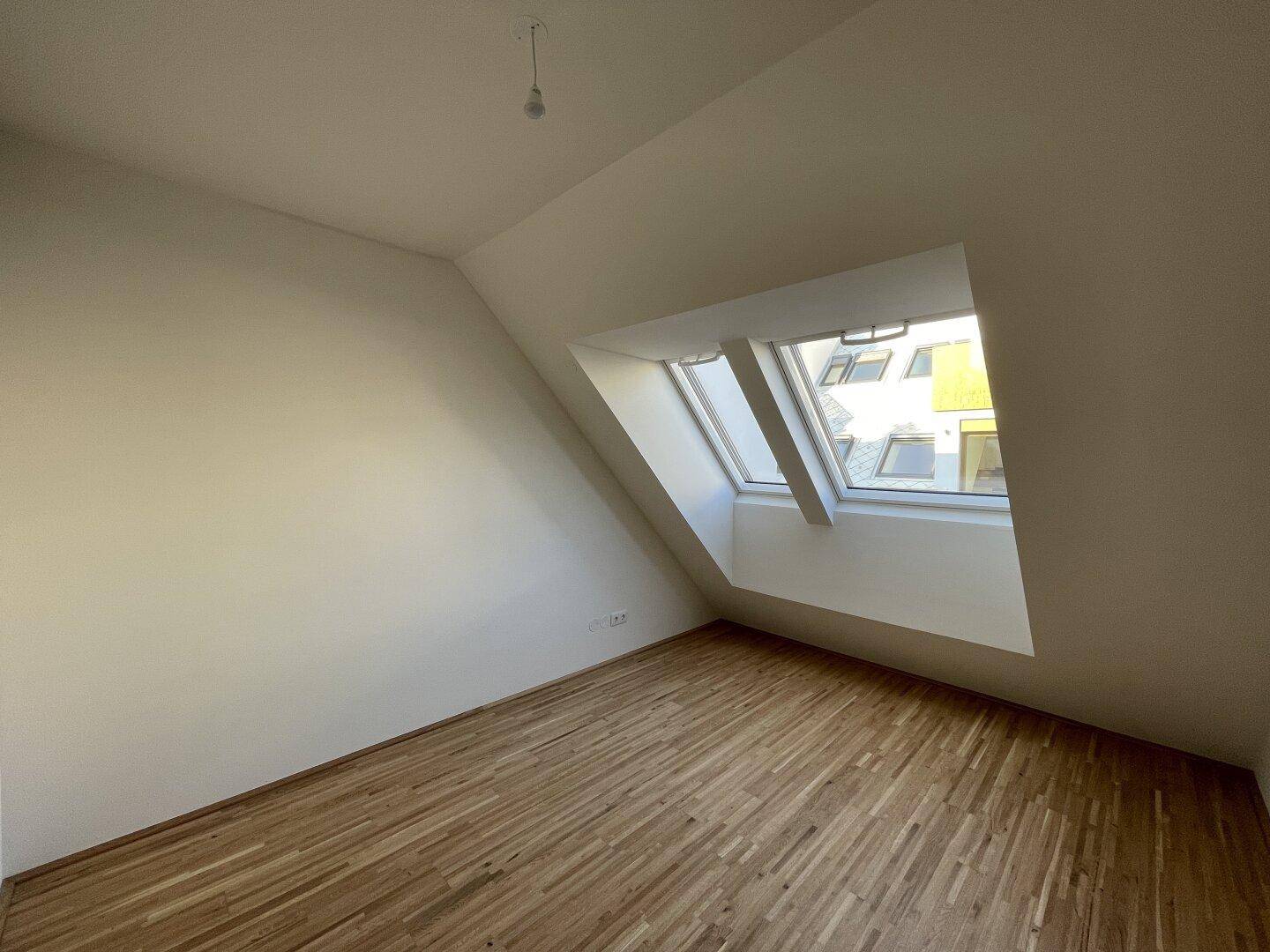 Helles Zimmer mit Dachschräge und großem Dachfenster, ideal als Schlaf- oder Arbeitszimmer.