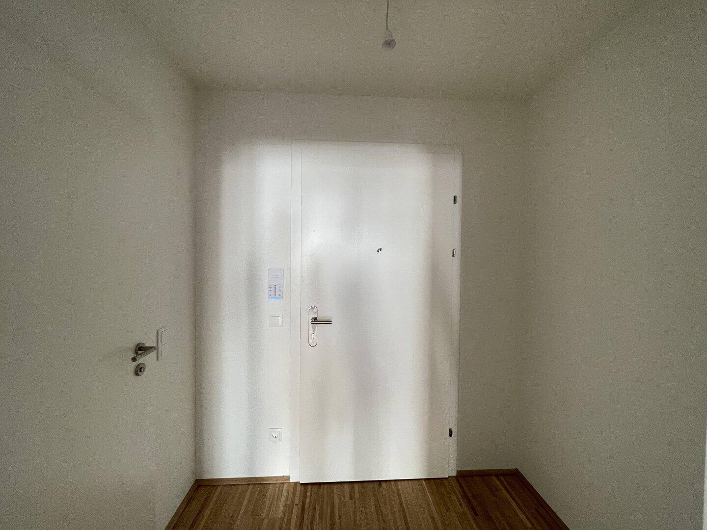 Eingangstür in einem hellen Flur mit Holzboden, bietet Sicherheit und Privatsphäre für die Bewohner.