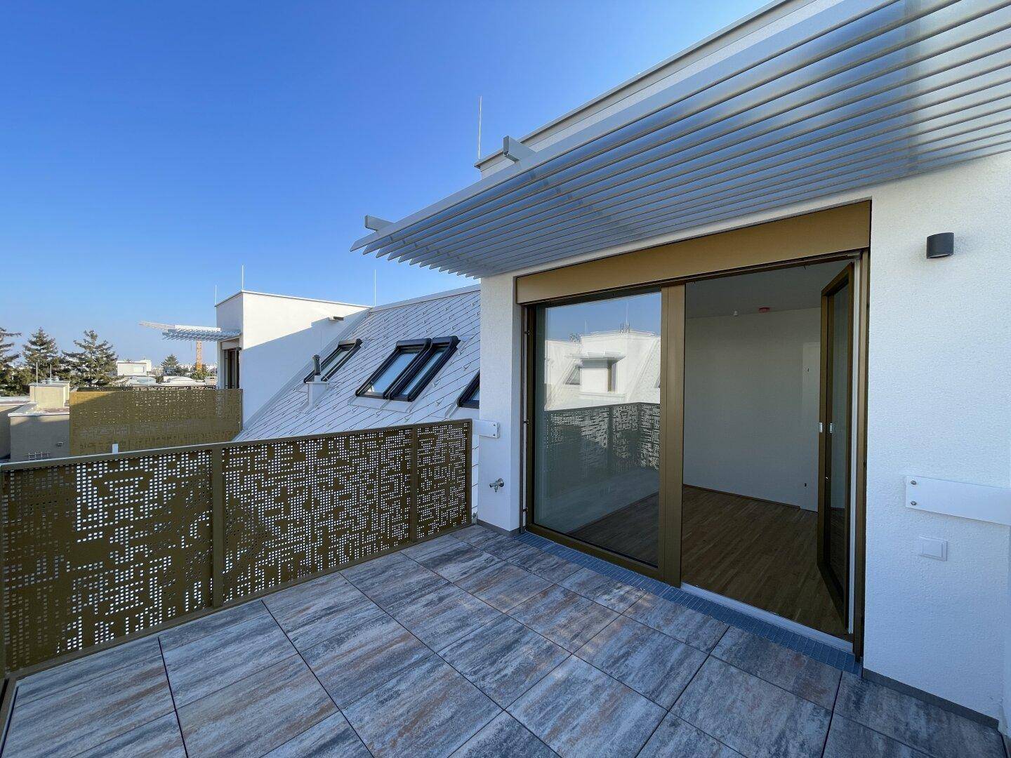 Dachterrasse mit Fliesenboden und Schiebetür, die in den Innenraum führt.