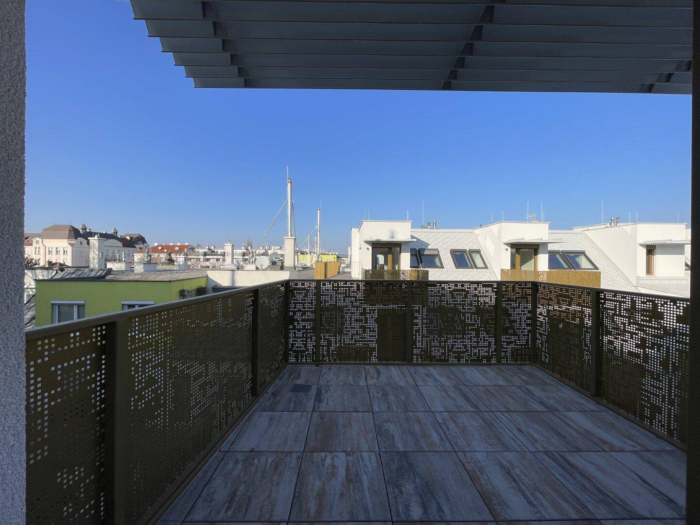 Geräumige Dachterrasse mit modernen Fliesen, perforiertem Geländer und Stadtblick.