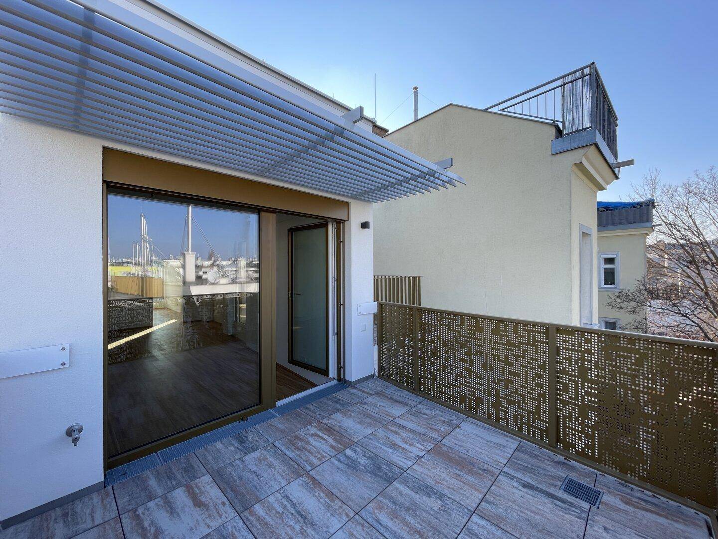 Sonnige Terrasse mit modernem Design, Fliesenboden und Zugang zum Innenbereich.