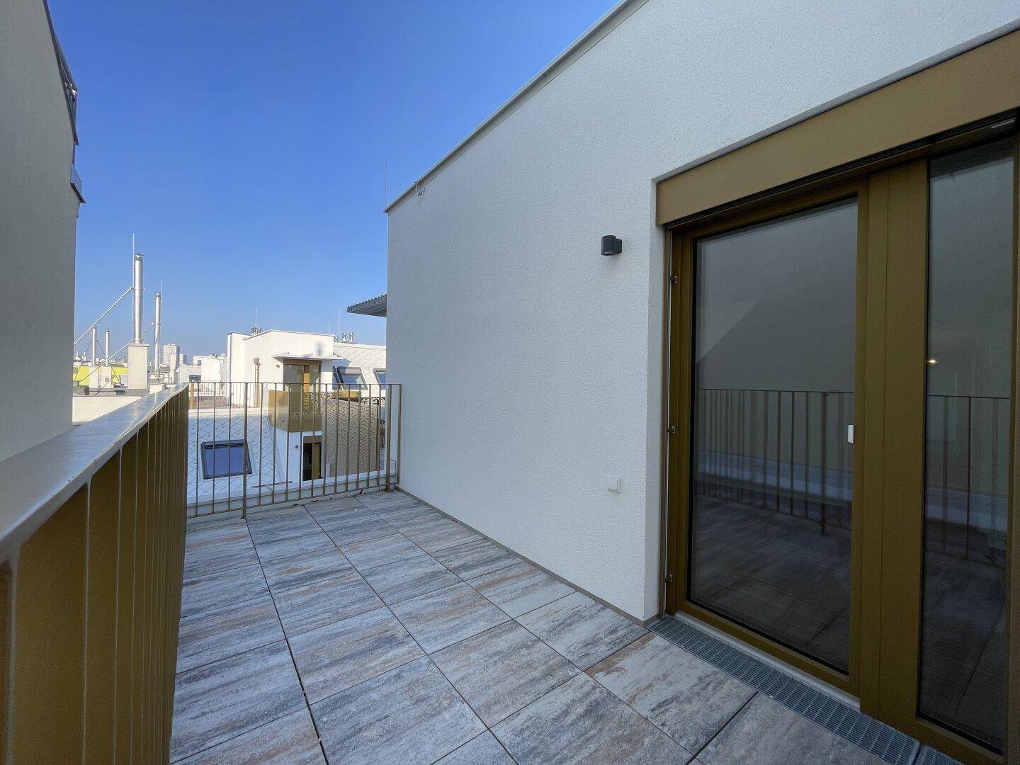 Terrasse mit Fliesenboden und Blick auf die umliegenden Dächer und Gebäude.
