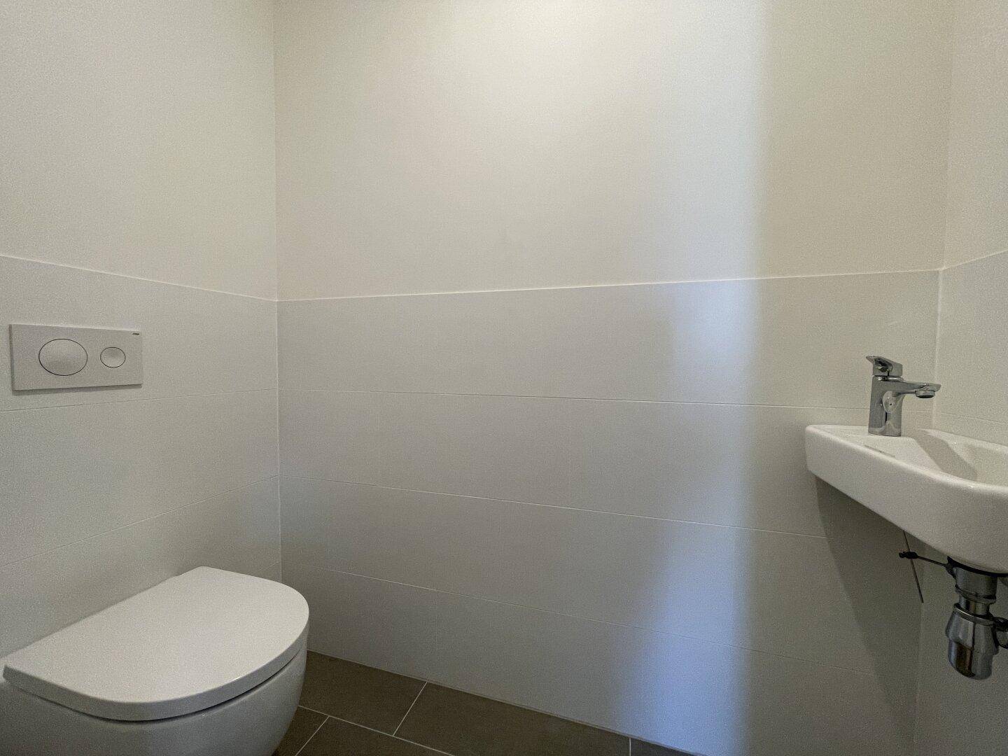 Modernes Gäste-WC mit wandhängender Toilette und kleinem Waschbecken.