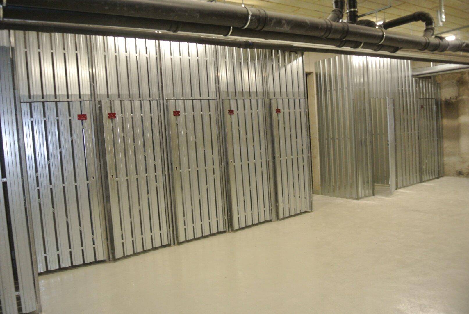 Geräumiger Kellerbereich mit zahlreichen Metall-Lagerabteilen für die Bewohner des Gebäudes.