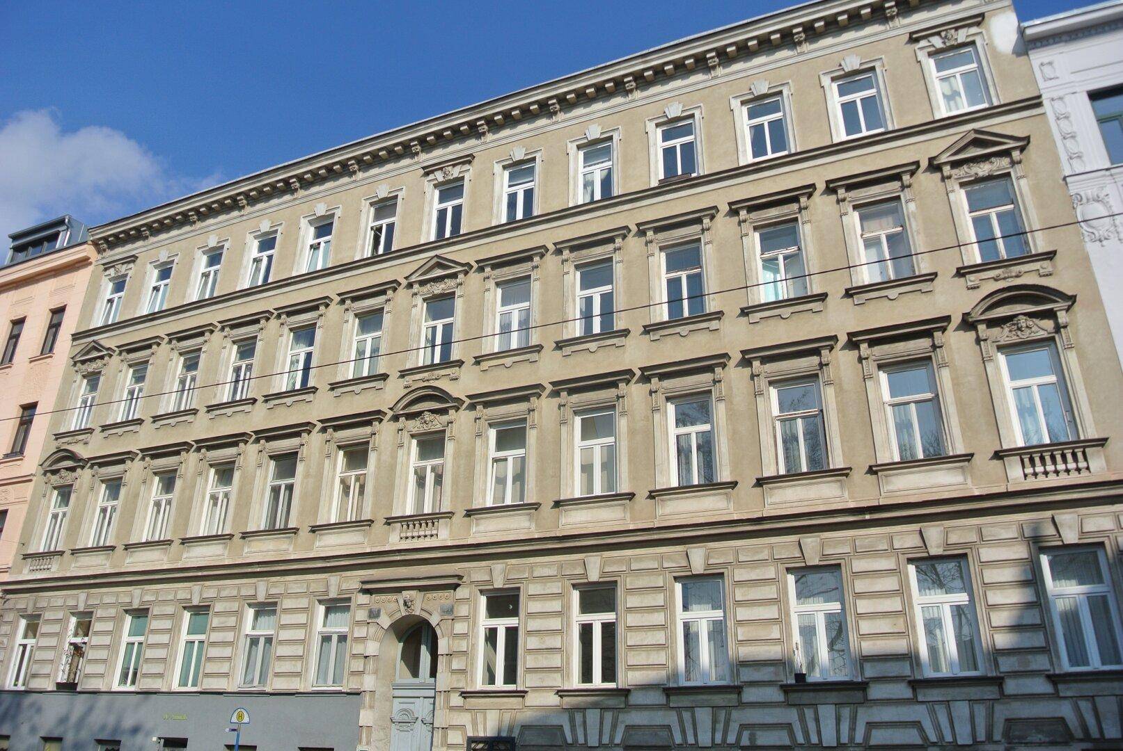 Gesamtansicht der historischen Fassade eines Altbaus mit vielen Fenstern und dekorativen Elementen.