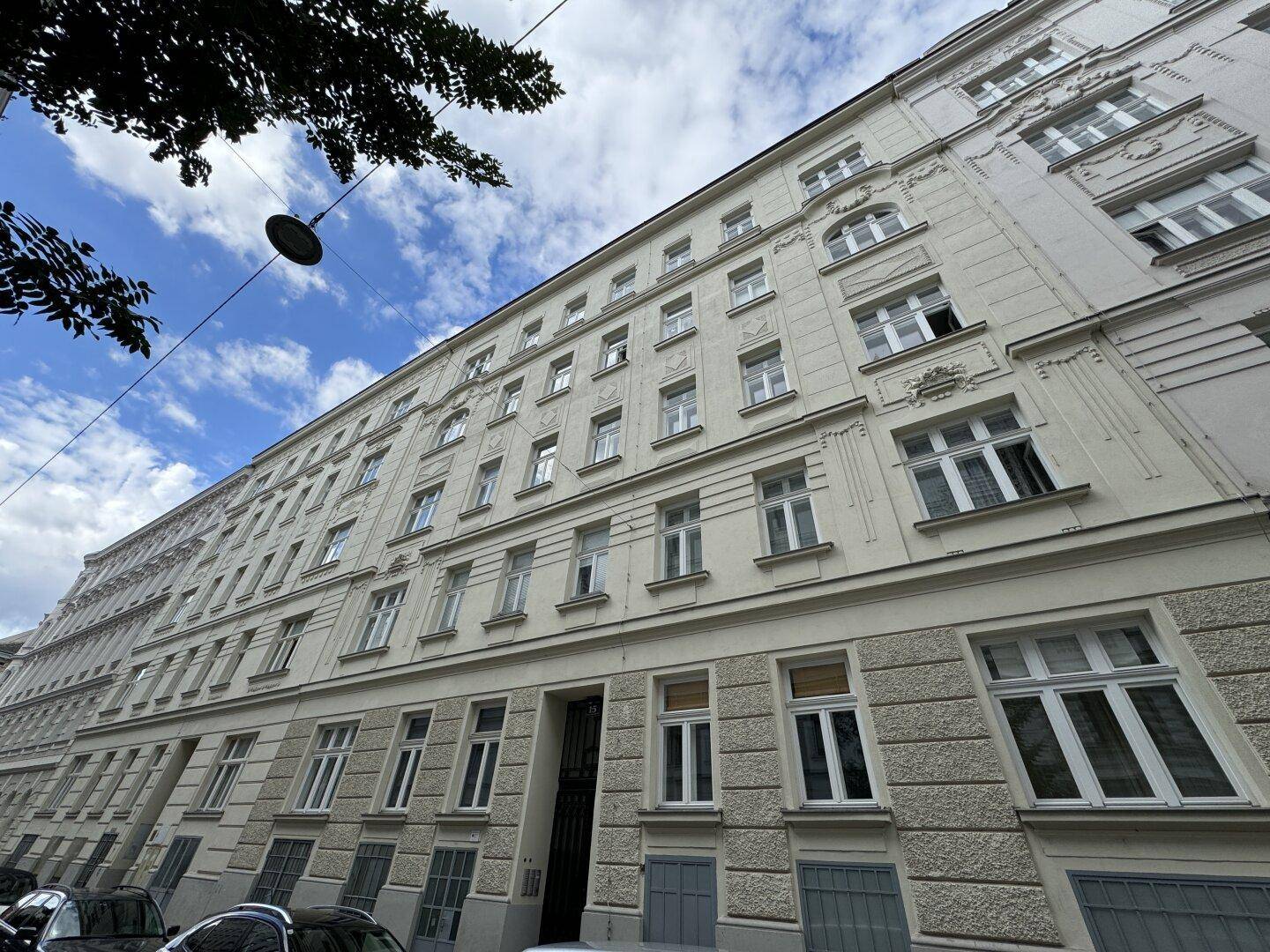 Langes, mehrstöckiges Altbaugebäude mit vielen Fenstern und dekorativer Fassade unter bewölktem Himmel.