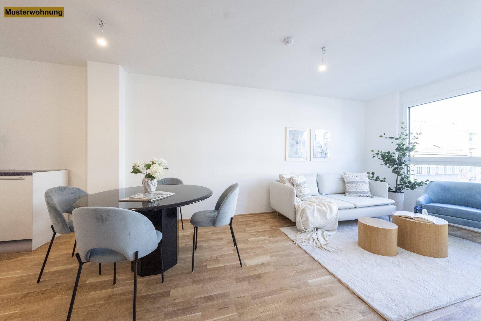 Offener Wohn-Essbereich mit Holzboden, modernem Esstisch und hellem Sofa vor großen Fenstern.