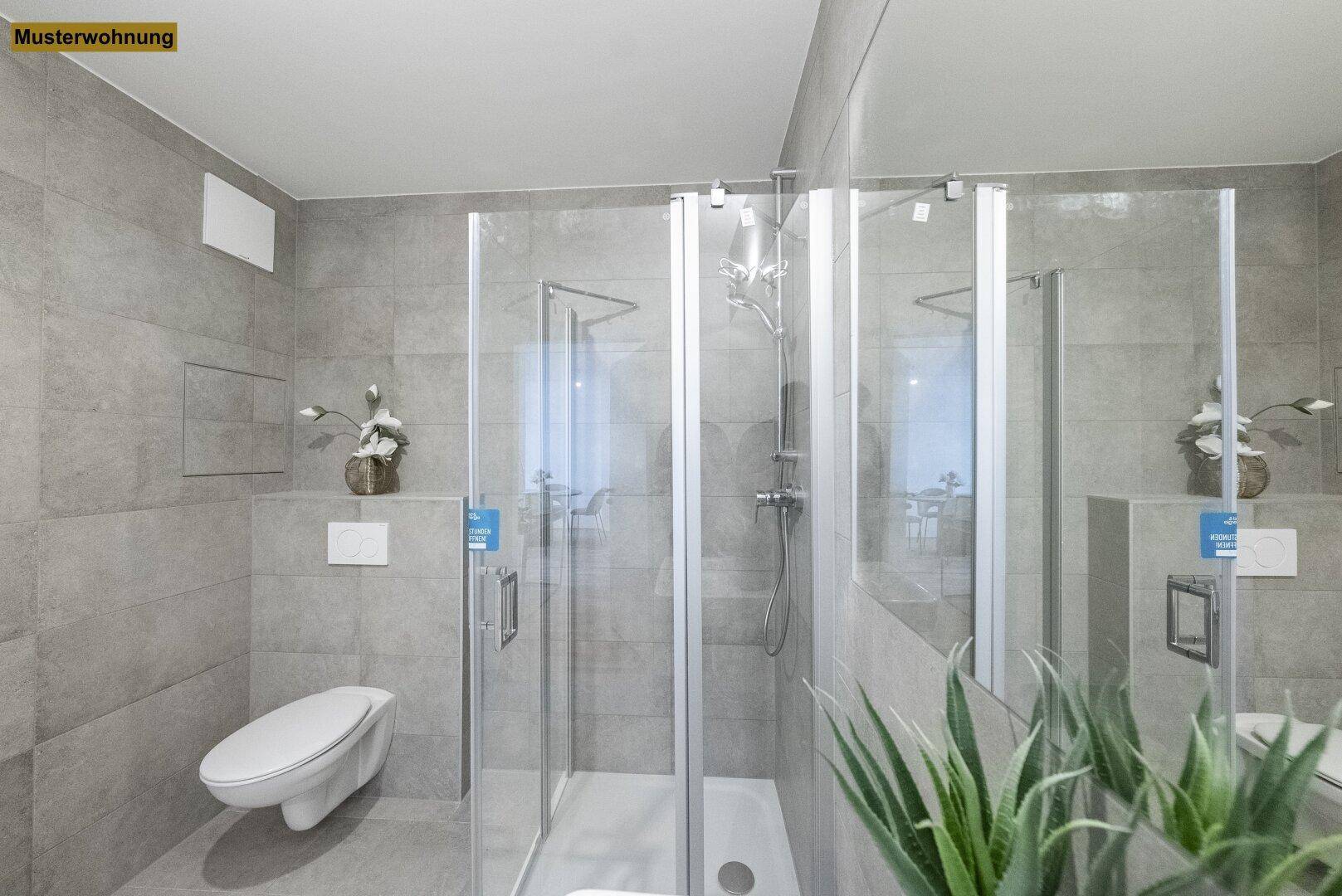 Modernes Badezimmer mit grauen Fliesen, Duschkabine und wandhängendem WC.