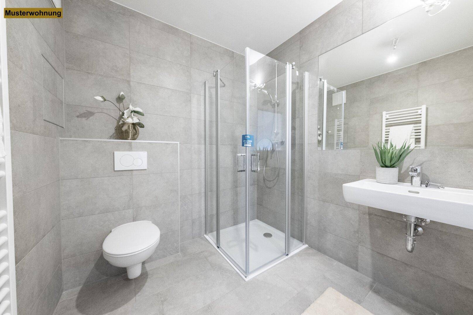 Modernes Badezimmer mit grauen Fliesen, Duschkabine und wandhängendem WC.