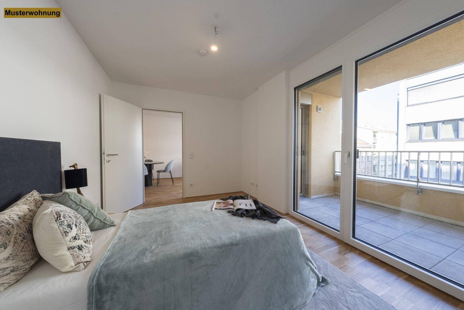 Schlafzimmer mit Balkonzugang und Blick in einen angrenzenden Wohnbereich.