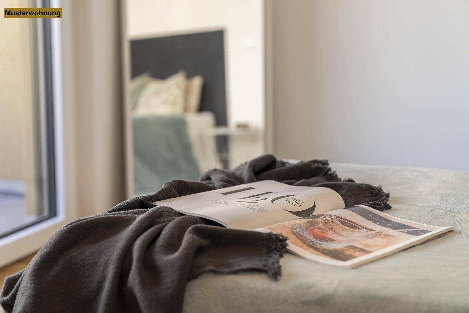 Gemütlicher Schlafbereich mit einer dunklen Decke und Magazinen, die zum Entspannen einladen.