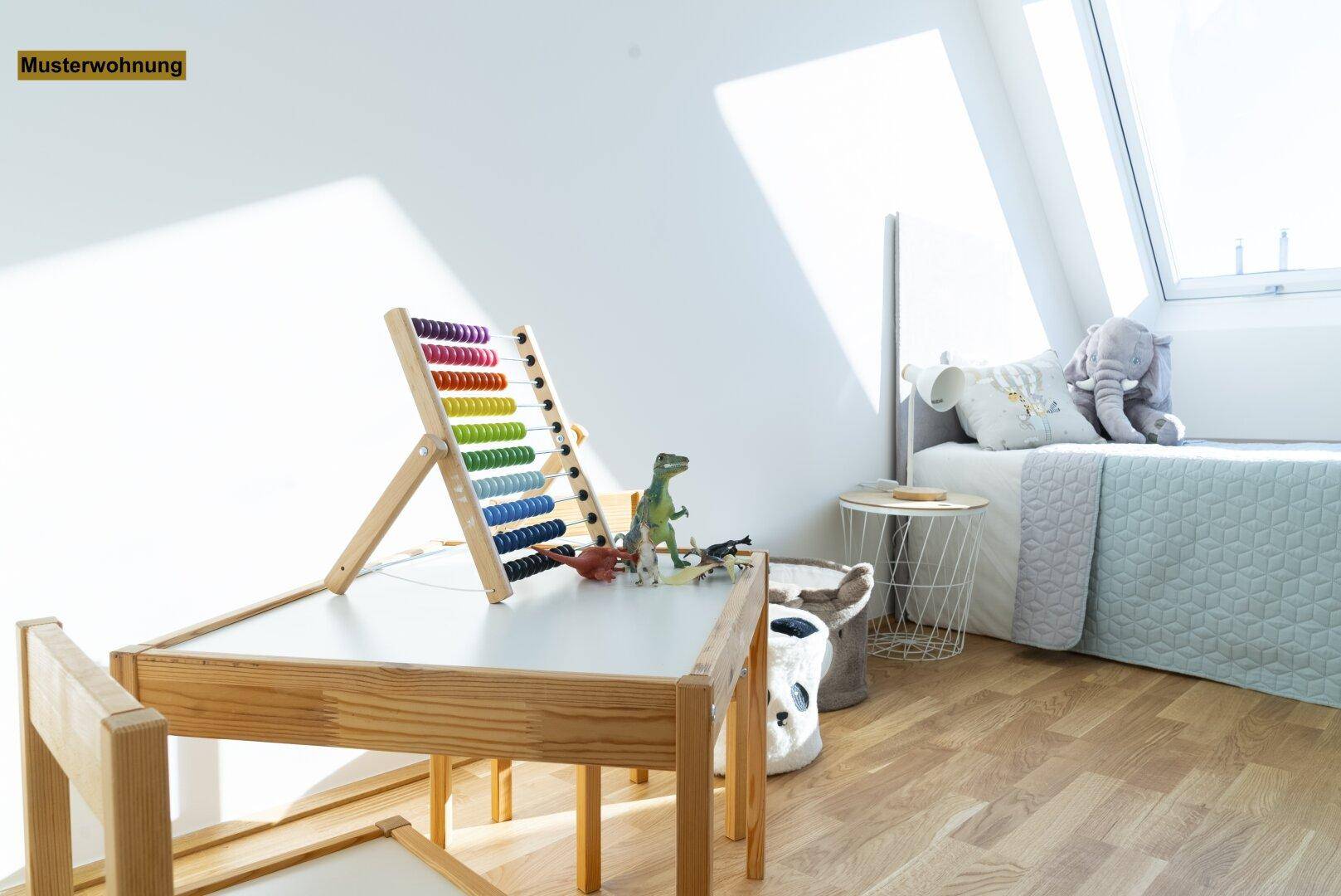 Freundliches Kinderzimmer mit Spieltisch, Rechenrahmen und Bett, beleuchtet durch ein Dachfenster.