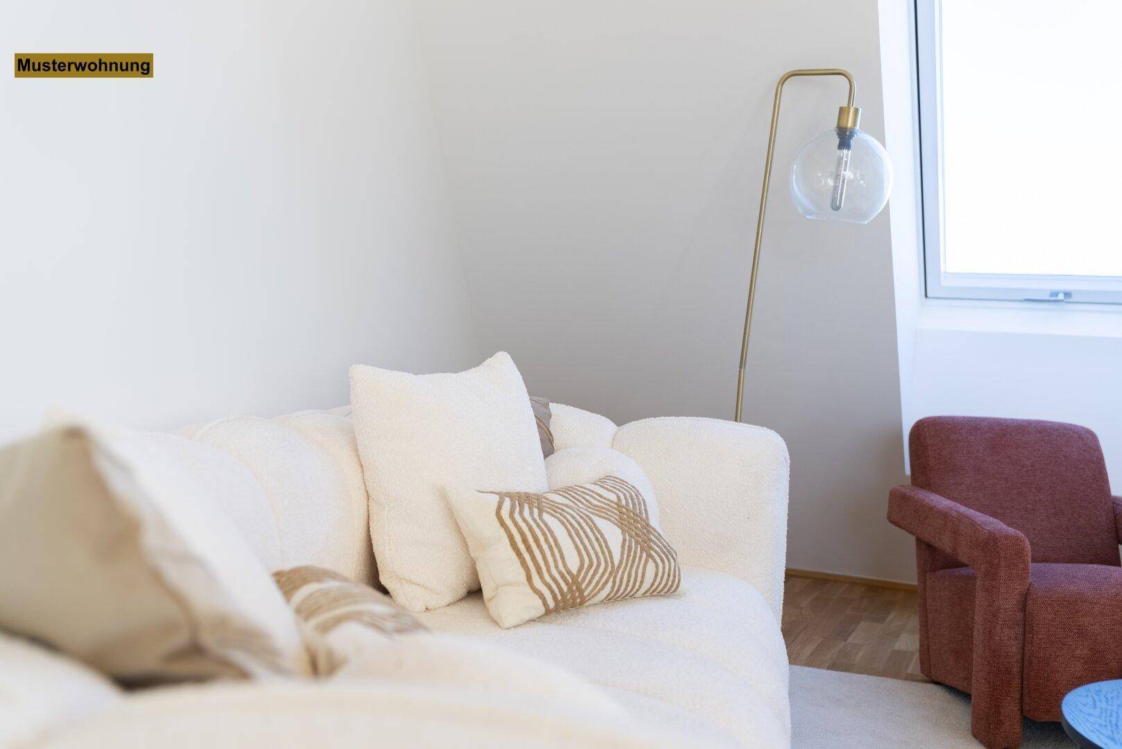 Gemütliches Wohnzimmer mit weißem Sofa, moderner Stehlampe und hellem Dachfenster.