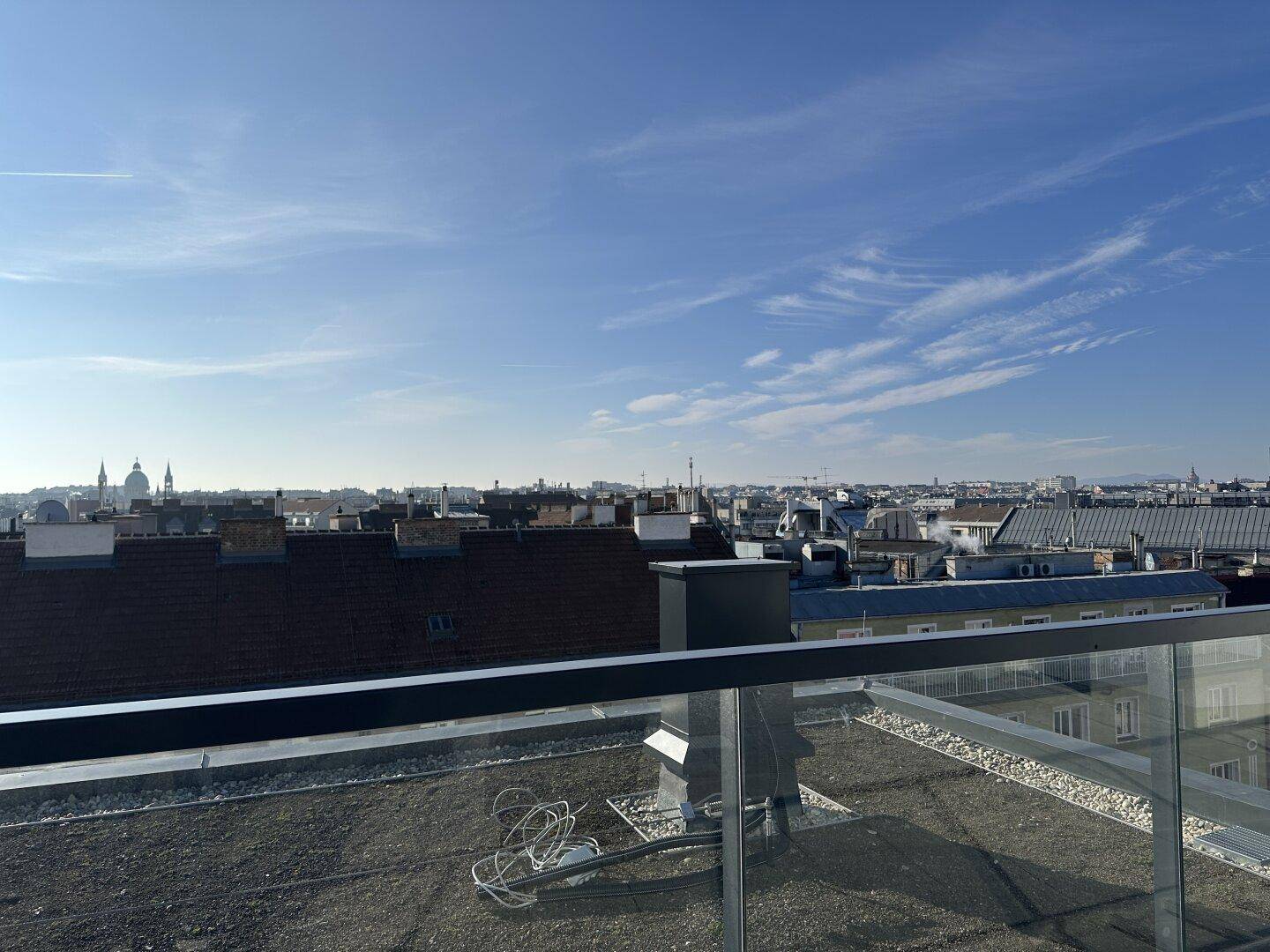 Panoramablick über die Dächer der Stadt Wien von einer modernen Dachterrasse aus bei Sonnenschein.