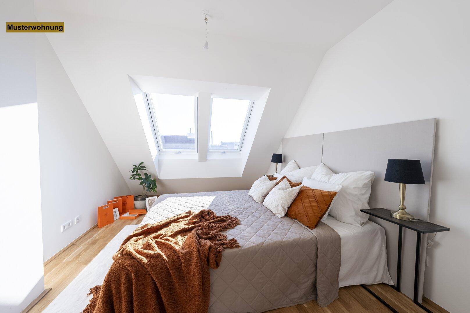 Helles Schlafzimmer mit Holzboden, Dachschrägen und zwei Dachfenstern, die den Raum mit Licht füllen.