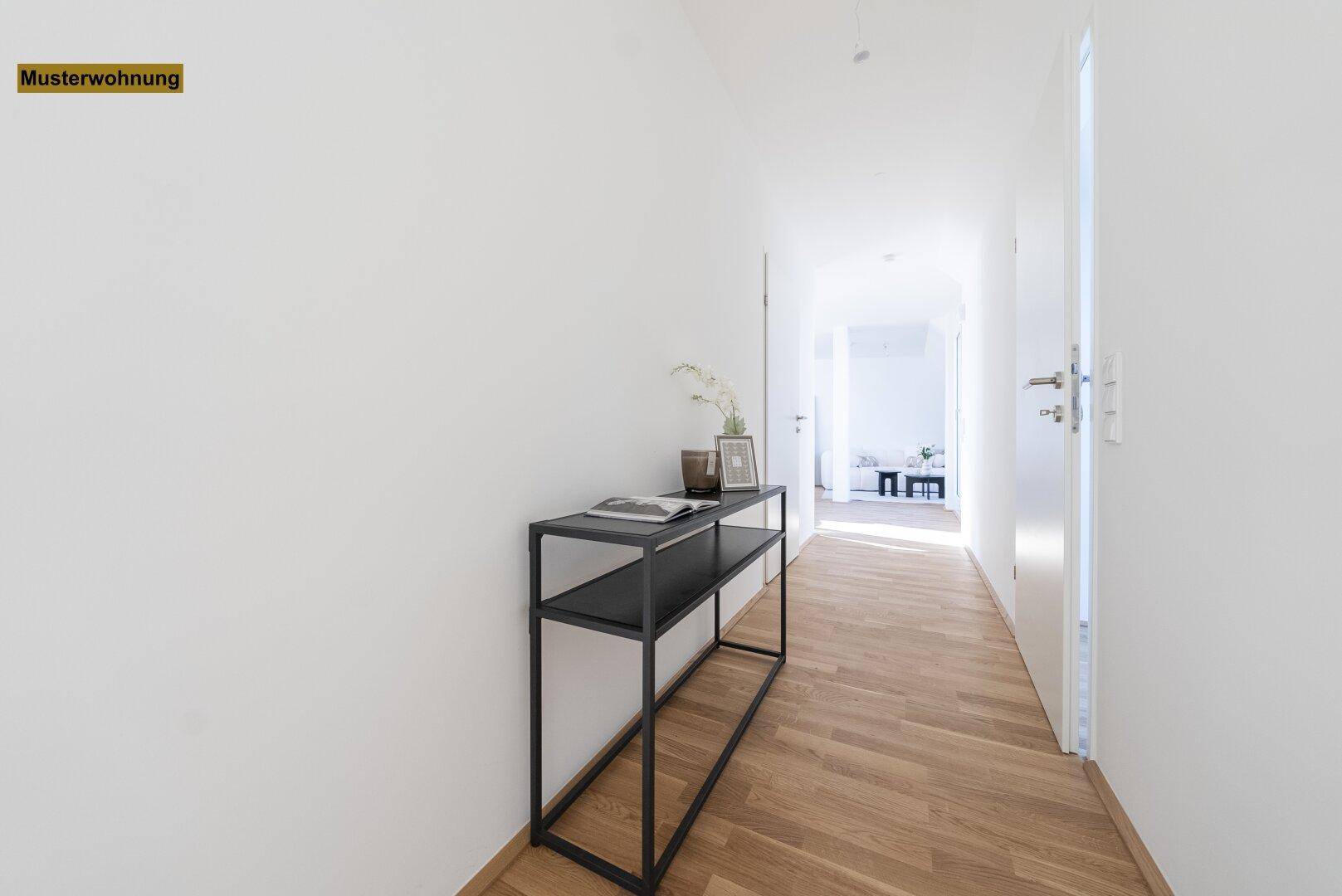 Langer, heller Flur mit Holzboden und minimalistischer Konsole, der zu den Wohnbereichen führt.