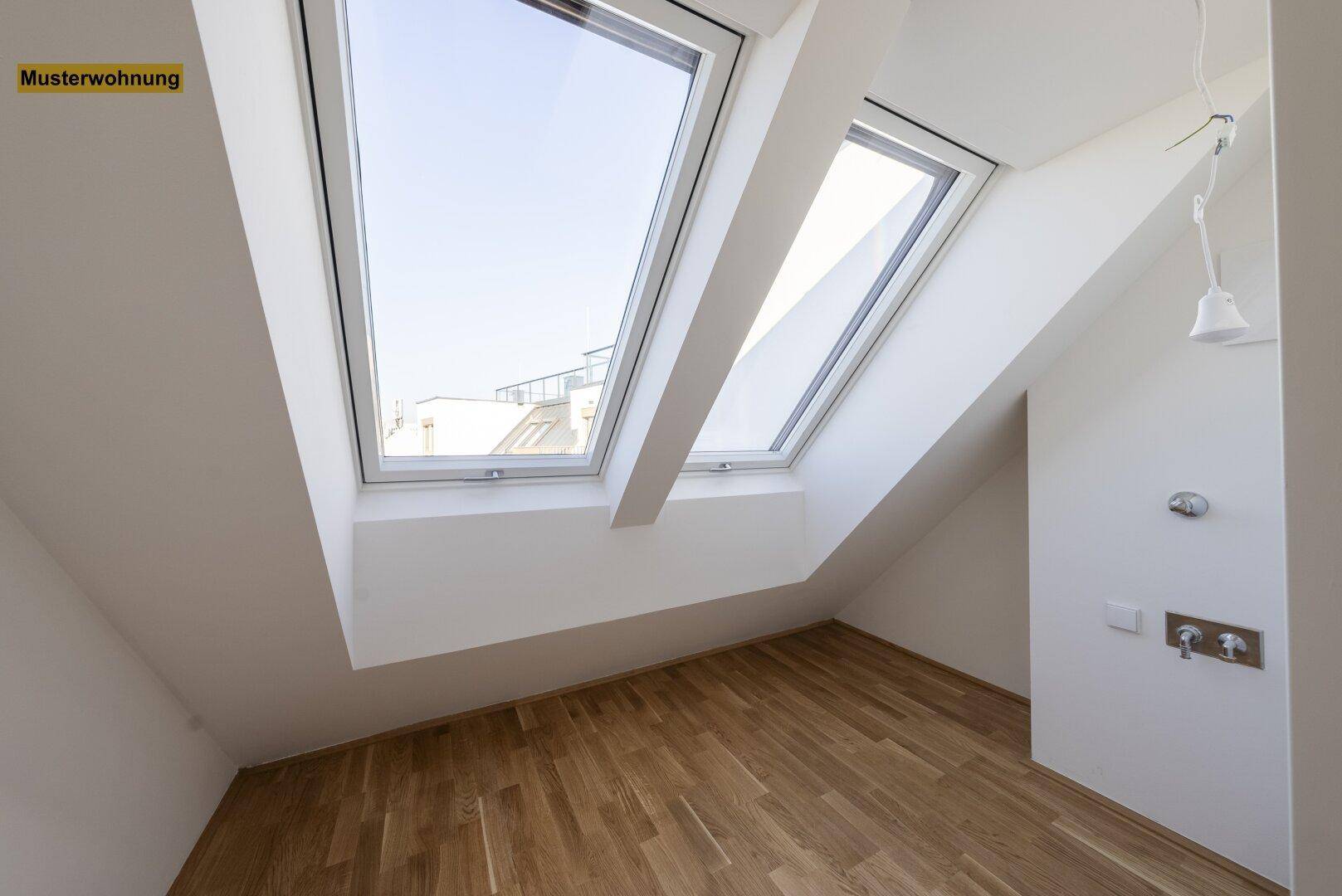Heller Raum im Dachgeschoss mit Holzboden und zwei großen Dachfenstern, bereit zur individuellen Gestaltung.